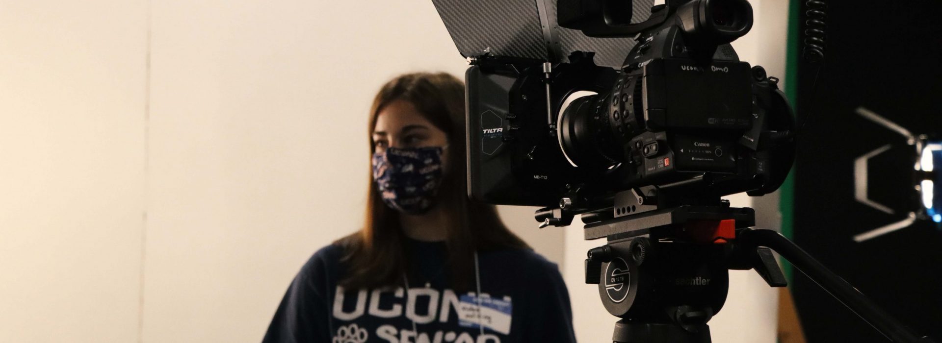 Video equipment and UConn Student wearing a UConn Senior shirt in the background